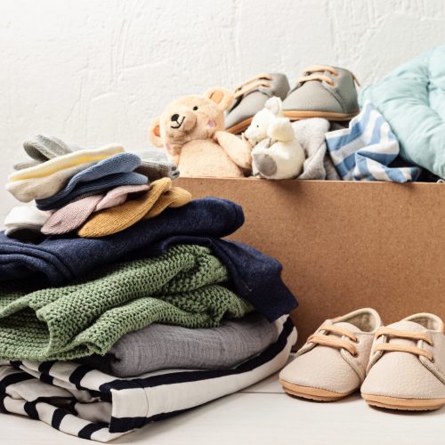 Baby and child clothes, toys in box. Second hand apparel idea. Circular fashion, donation, charity concept